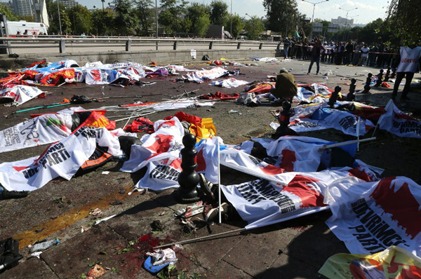 A man squats over a body lying on the ground following an explosion at the main train station in Turkey's capital Ankara, on October 10, 2015. At least 30 people were killed in twin explosions in Turkey's capital Ankara, targeting activists gathering for a peace rally organised by leftist and pro-Kurdish opposition groups. AFP PHOTO / ADEM ALTAN